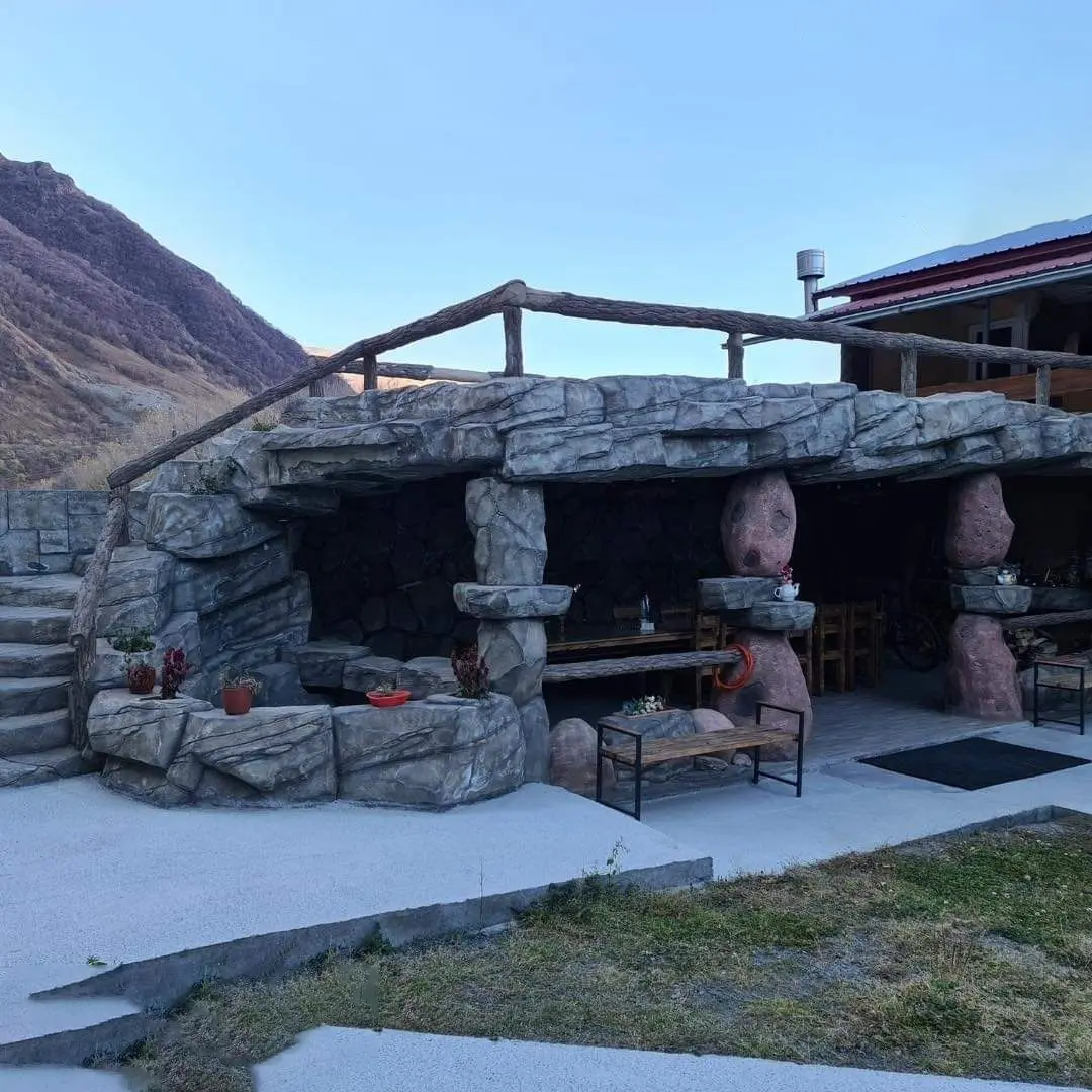Terrasse extérieure avec structure en béton sculpté façon grotte, mobilier bois et ambiance naturelle – Réalisation Art Déco Béton