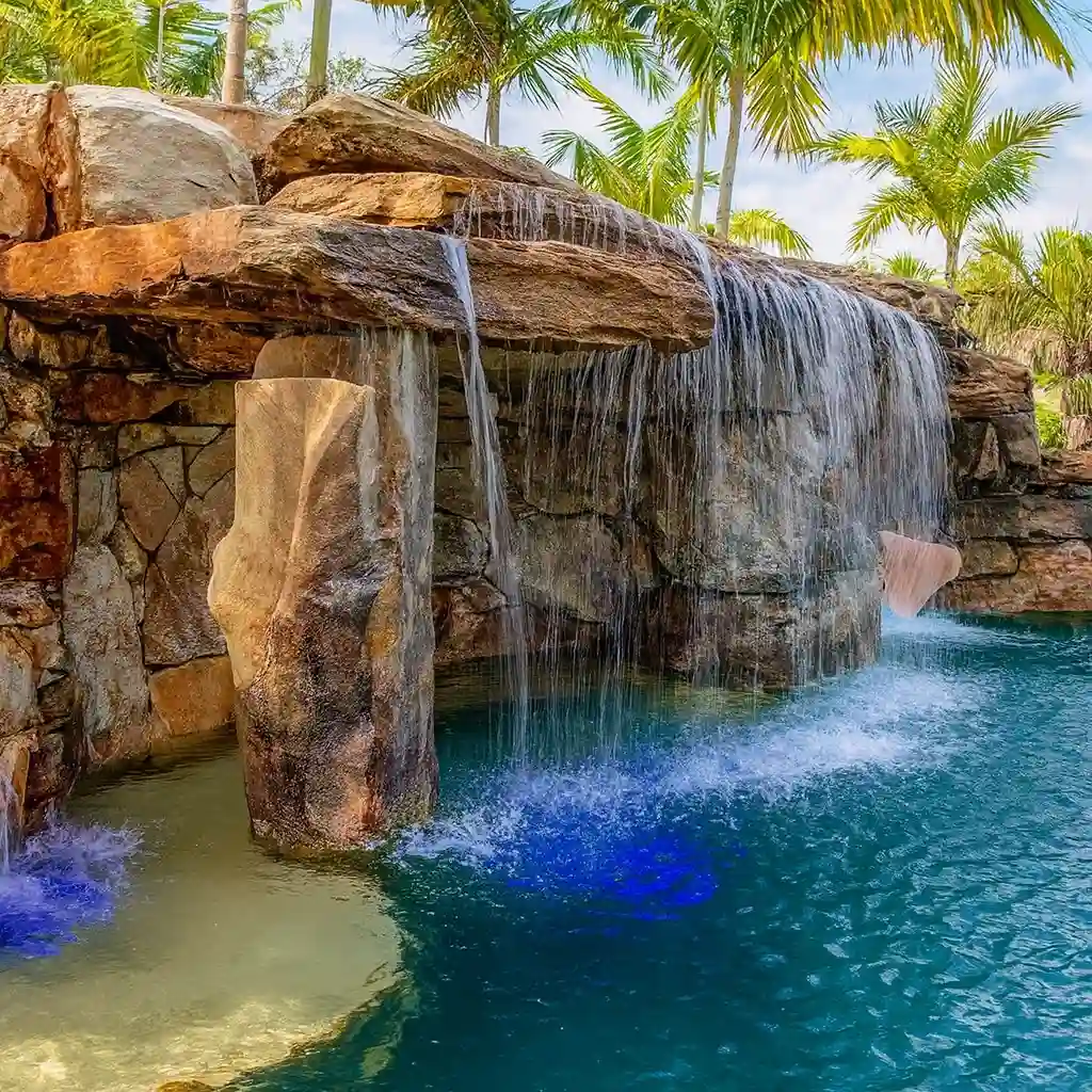 Cascade tropicale en béton sculpté Art Déco 34 intégrée à une piscine avec éclairage bleu